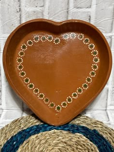 a heart shaped tray sitting on top of two straw baskets next to each other with beaded hearts in the middle