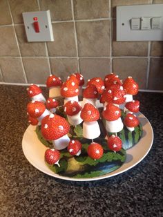 a plate with strawberries and mushrooms on top of watermelon in front of a light switch