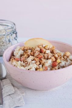 a pink bowl filled with cereal and an apple