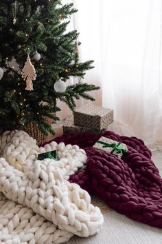 a christmas tree with presents under it next to a pile of blankets