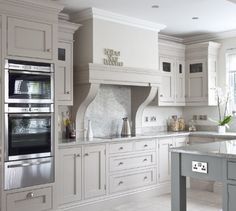 a kitchen with white cabinets and an island in front of the stove top ovens