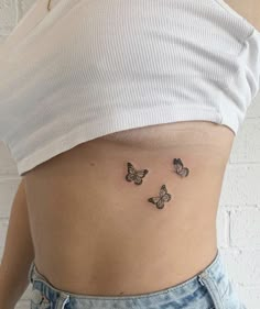 a woman's stomach with three small butterflies on the side, all around her