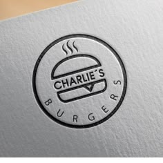 the logo for charlie's burgers is shown in black and white on a silver background