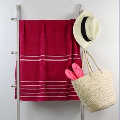 a towel and hat hanging on the wall next to a towel rack with two towels