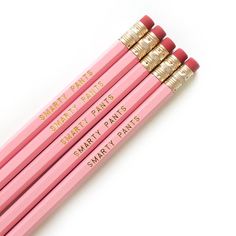 four pink pencils with gold tips are lined up on a white surface and have the words smart plans written on them