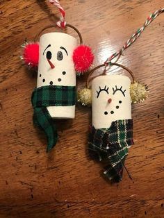 two toilet paper roll snowmen hanging on a wooden table