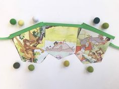 several disney pictures hanging from green string on white surface with balls around them and small beads scattered about