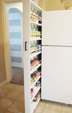 a white refrigerator freezer sitting inside of a kitchen next to a pantry filled with food