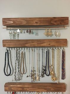 a wooden shelf with several necklaces hanging from it's sides and on the wall