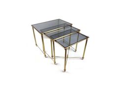 two glass and brass nesting tables on wheels