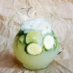 a pitcher filled with cucumber slices on top of a white cloth covered table