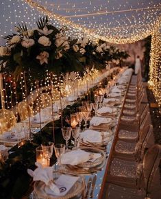 a long table is set with white flowers and place settings for an elegant dinner party