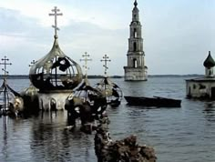 an old church in the middle of water with crosses on it's spires