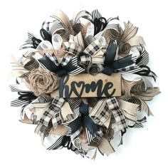 a wreath with the word home spelled in black and white ribbon on top of it