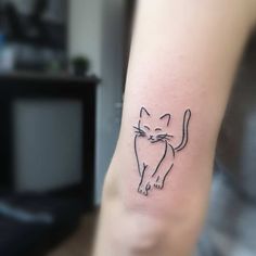 a small black cat tattoo on the wrist