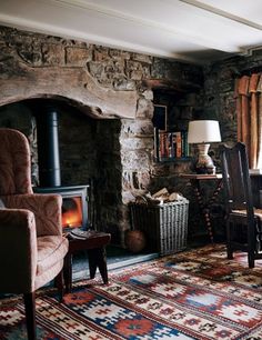 a living room filled with furniture and a fire place next to a stone fireplace covered in logs