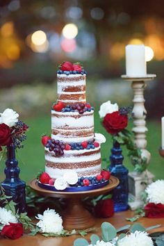 a multi layered cake sitting on top of a wooden table next to flowers and candles