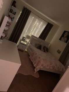 a bedroom with a bed, desk and window covered in sheer curtains on the windowsill