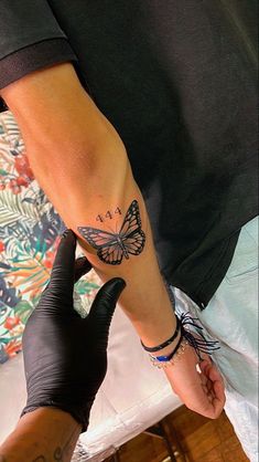 a person with a butterfly tattoo on their arm and wrist is getting inked by someone else