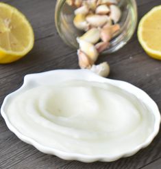 a bowl of yogurt next to sliced lemons and nuts on a table