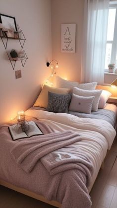 a bed with blankets, pillows and lights on the headboard in a small room