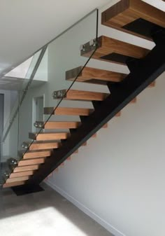 a stair case with glass railing and wooden handrail