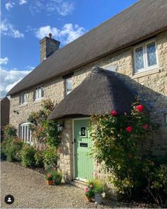 a thatched roof house with roses growing around the front door and window sill