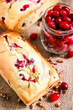 cranberry bread is cut in half and sitting on a table next to some cranberries