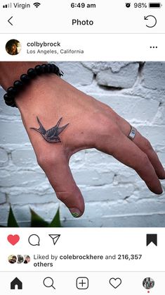 a person's hand with a bird tattoo on it