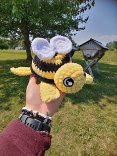 a hand holding up a stuffed animal in the shape of a bee with two wings