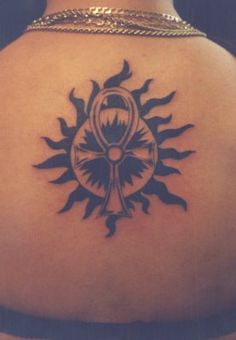 the back of a woman's neck with a sun tattoo on her left shoulder