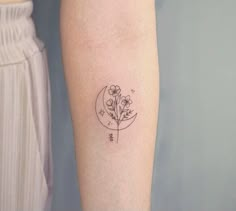 a small flower and moon tattoo on the arm