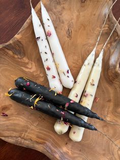 four white candles are on a wooden tray