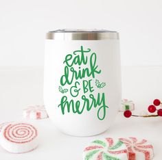 a white cup with green lettering on it next to candy canes and candies