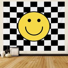 a yellow smiley face on a black and white checkered wall hanging in an empty room