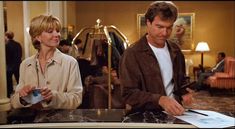 a man and woman standing at a counter in a hotel lobby looking at something on the table