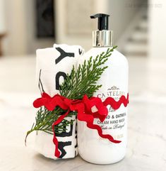 a bottle of soap with a red ribbon tied around it sitting on top of a counter