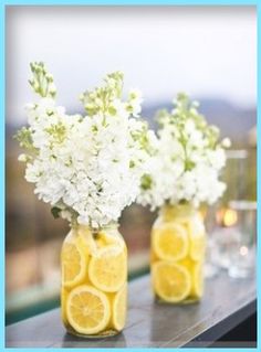 three mason jars filled with lemons and white flowers