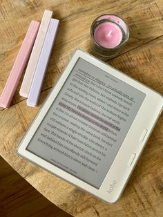 a tablet sitting on top of a wooden table next to a pink candle