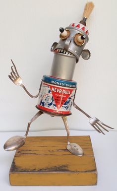 a metal toy with forks and spoons in it's arms, on top of a wooden board