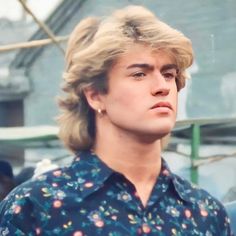 a young man with blonde hair wearing a blue shirt and looking off to the side