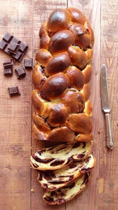 a loaf of bread sitting on top of a wooden cutting board next to chocolate chunks