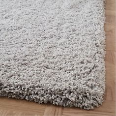 a white rug on top of a wooden floor with a wood flooring area in the background