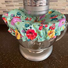 a close up of a blender on a counter with a flowery cloth covering it