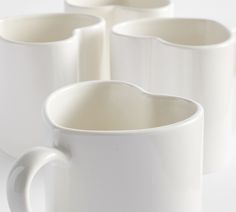 four white coffee mugs sitting next to each other