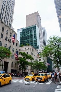 taxi cabs are parked in front of tall buildings on a city street with american flags