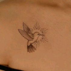 a small bird tattoo on the back of a woman's left shoulder and neck