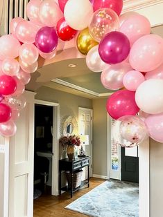 a bunch of balloons are hanging from the ceiling in front of an entrance to a house