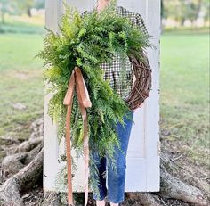 a woman standing in front of a door holding a wreath