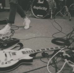 a black and white photo of someone's feet with their shoes on top of guitars